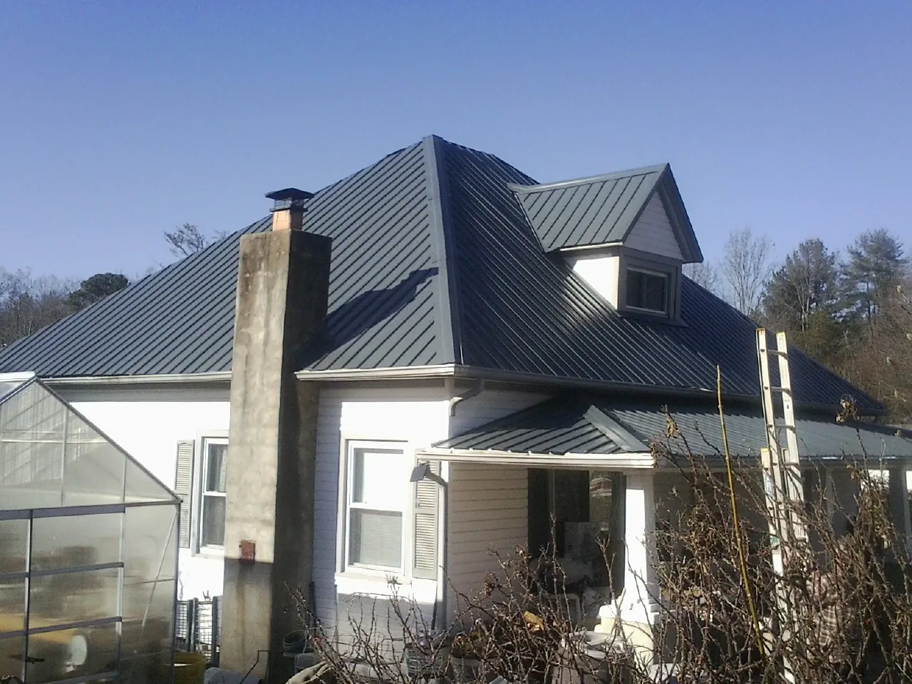 Dark blue standing seam metal roof on a white farmhouse with dormer — Slate & Tile Roof Repair by Roofing Brothers in Fresh Meadows