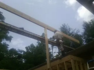 Carpenter setting a ridge beam over a new addition frame — Ice Dam Removal by Roofing Brothers in Fresh Meadows