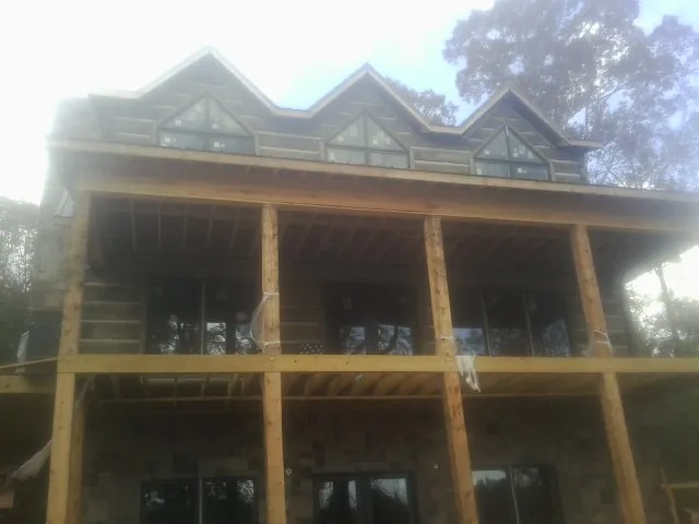 Dormers and porch framing on a large log home under construction — Roof Coating work by our crew in Fresh Meadows
