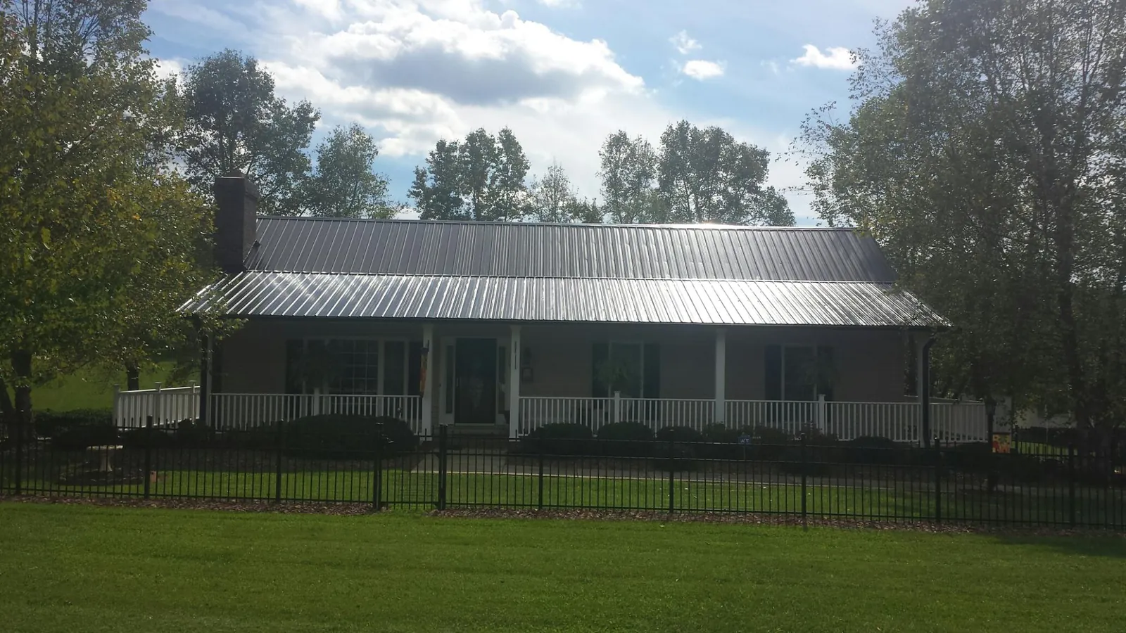 Gray metal roof on a brick ranch with a full width front porch — Gutter Guard Installation work by our crew in Fresh Meadows