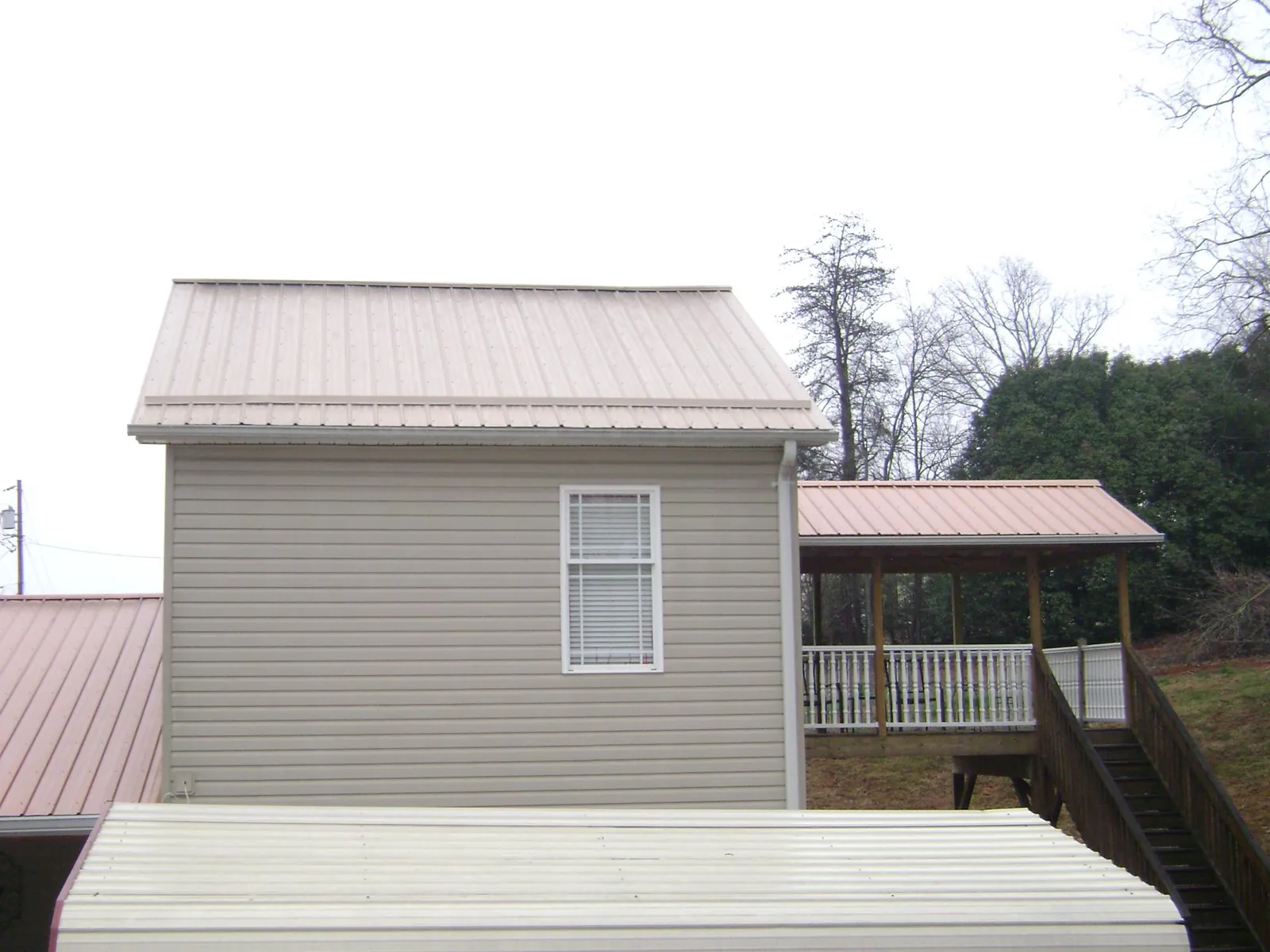 Tan metal roofs on a two story addition and attached porch, from a Roof Replacement job in Fresh Meadows