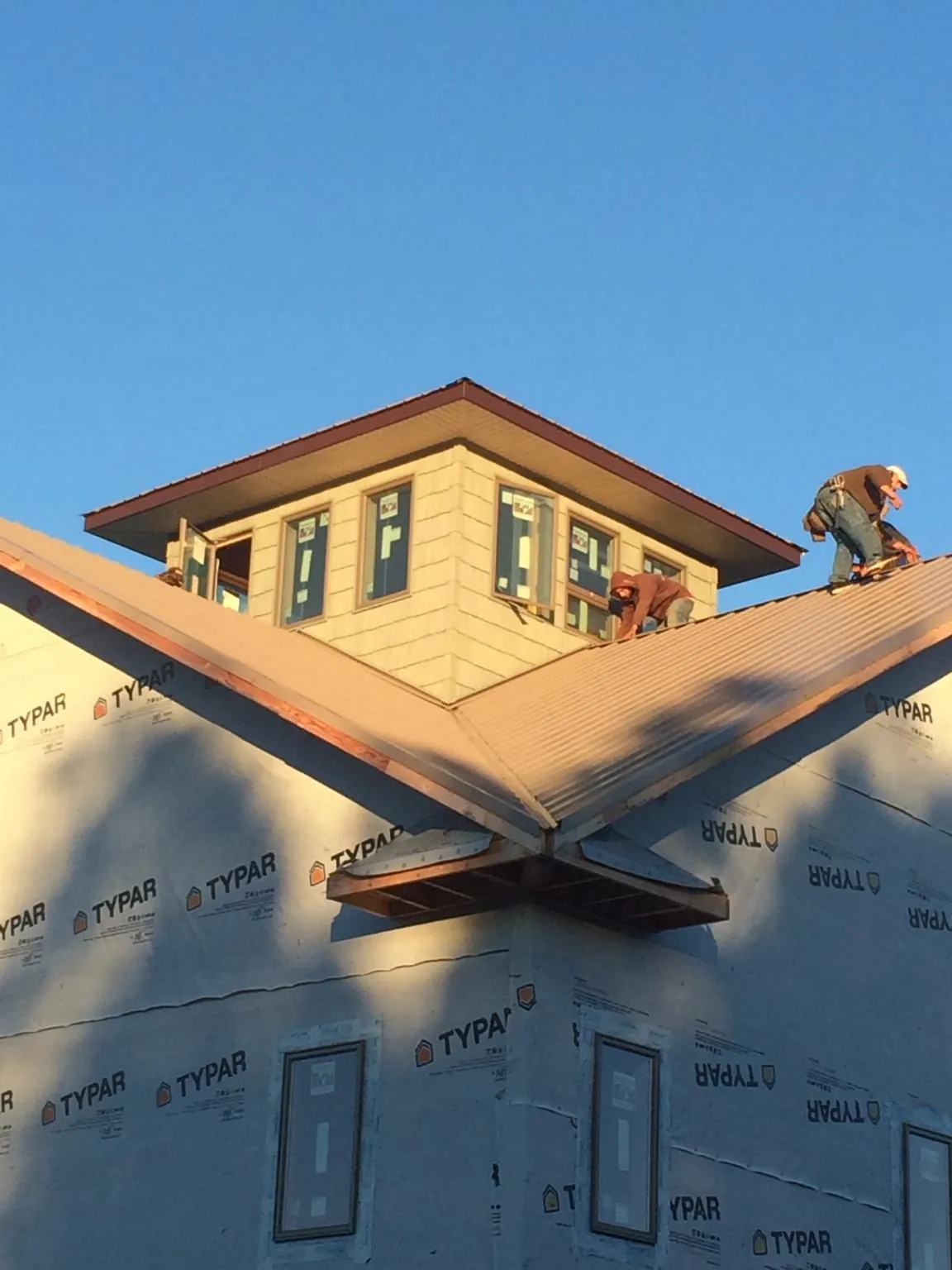 Roofers working around a rooftop cupola on a new metal roof at sunset — Roof Waterproofing in Fresh Meadows by Roofing Brothers